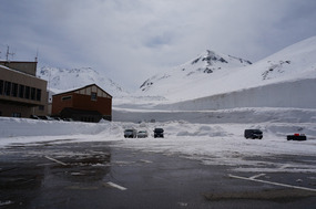 Massive snow wall, with snowboarders on the slopes
