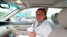 Gudi im Auto mit einem Kaffee to Go