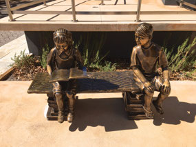 Bronze statue of kids reading outside Library