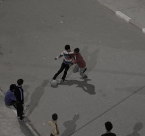 Kids playing soccer outside our apartment at night