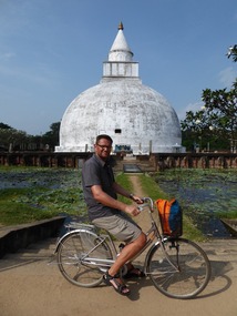 Grote man op kleine fiets voor enorme stupa