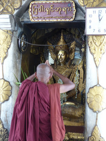 Monk praying to the ruby Buddha