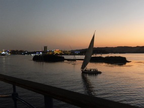 GRACEFUL FELUCCA WITH THE LIGHTS OF ASWAN BEHIND