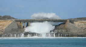 Truck on bridge doused by a crashing wave